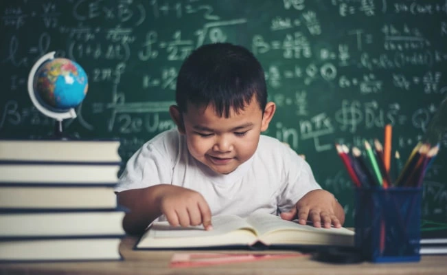 Young student with glasses focused on writing.